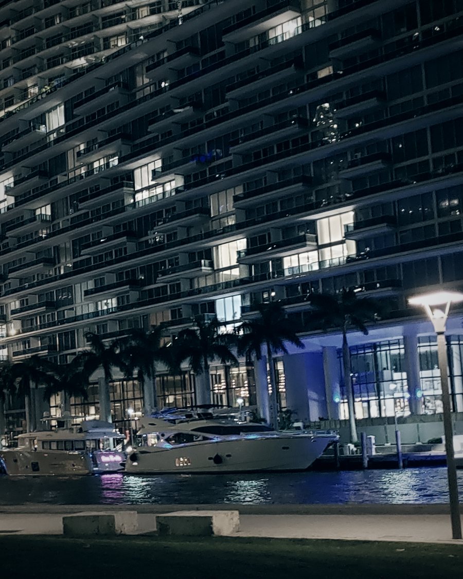 Brickell condo towers and yachts along the Miami River at night, seen from the Riverwalk