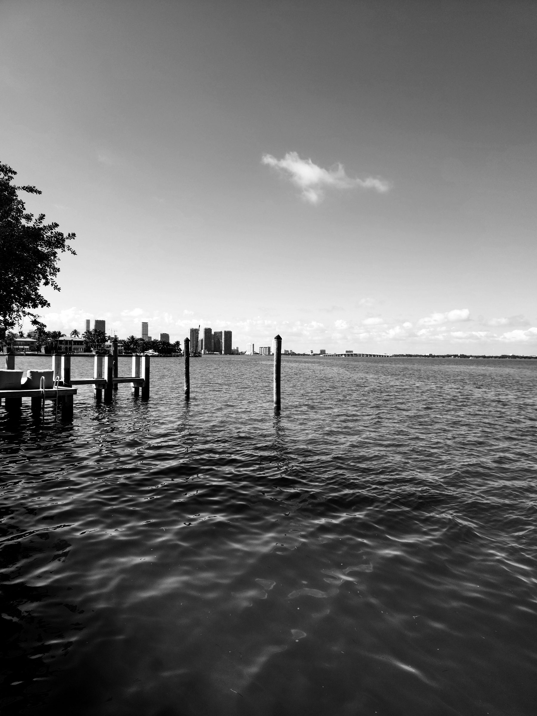 A private dock on Biscayne Bay with the Miami skyline in the distance, in black and white